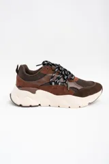 Zapatilla urbana de diseño chunky, combinando paneles de gamuza y cuero en tonos chocolate con malla técnica. Presenta cordones bicolores y una suela de plataforma de goma en color crema.