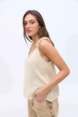 Musculosa de punto azul marino con brillo de lurex, escote redondo y breteles anchos decorados con rulos tejidos.