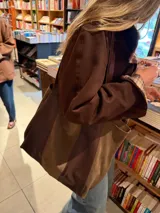 Bolso tipo shopper de gran tamaño, confeccionado en una combinación de cuero y gamuza en tonos marrones. Presenta un diseño bicolor con paneles verticales, doble asa de hombro y bolsillo interior.