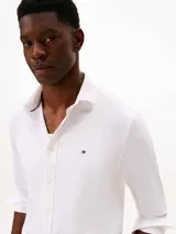 Camisa de corte regular fit confeccionada en tejido twill técnico de nylon y elastano. Presenta cuello clásico, cierre frontal con botones y el logo de la marca bordado en el pecho.