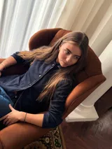 Blazer de jean azul con cuello, solapa y cuatro botones frontales. Presenta volados de encaje negro en cuello y delantero, mangas largas con pliegues y bolsillos plaqué. Interior con terminación en hilo bordó.