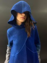 Tapado largo de lana merino color gris oscuro con teñido degradado en gris claro en ruedo, mangas y capucha. Tiene corte recto, bolsillos laterales y cierre cruzado con broches a presión ocultos en los hombros.