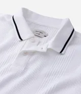Remera polo blanca de viscosa texturizada con rayas, cuello y puños de mangas cortas en ribana con detalles contrastantes en negro.