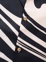 Camisa de manga corta con cuello tipo camp y estampado abstracto en tonos beige y negro.