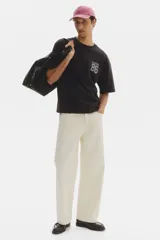 Remera de algodón en punto pesado color negro, de corte holgado con hombros caídos, cuello redondo acanalado y estampa frontal estilo universitario con el texto 'SOHO NYC 86'.