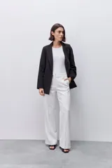 Pantalón de vestir tiro alto estilo wide leg, color blanco, de corte relajado y silueta amplia. Cuenta con cierre frontal y bolsillos laterales.