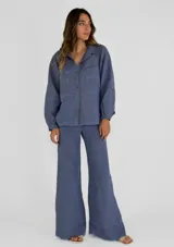 Chaqueta color amarillo de lino, con cuello camisero, cierre frontal con botones, mangas largas con puños abotonados y dos bolsillos de parche en el pecho.