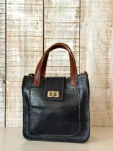 Mini bag de cuero color negro con efecto envejecido, asas de mano y detalles en cuero marrón tostado. Cuenta con un bolsillo frontal con solapa y cierre metálico giratorio, y costuras pespunteadas a la vista.