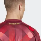 Camiseta de fútbol Adidas de la segunda equipación de la selección femenina de Alemania, color rojo oscuro con un estampado abstracto en tonos rojos y rosados. Presenta cuello redondo y detalles en amarillo neón en el logo y el escudo.
