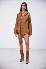 Camisa marrón de manga larga con detalles de lentejuelas y bordados en el frente. Tiene cuello clásico y botones frontales.