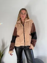 Campera con cierre frontal, de piel sintética color beige con detalles en marrón y negro.