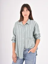 Camisa de corte holgado con estampado de rayas verticales en tonos verde y blanco, cuello clásico, cierre frontal con botones y bolsillo en el pecho.