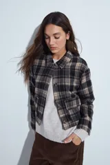 Campera de paño con diseño de cuadros en tonos negro, gris y beige. Presenta cuello camisero, cierre frontal con botones y corte corto.