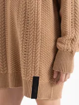 Sweater de punto color rojo con diseño de trenzas verticales y textura estructurada. Presenta cuello redondo, mangas largas y un corte holgado con terminaciones acanaladas.