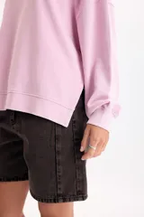 Buzo rosa de corte holgado y diseño liso, con cuello redondo, mangas largas y puños ajustados.
