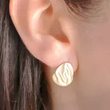Aros tipo botón dorados con textura ondulada.