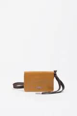 Billetera compacta de cuero color marrón con acabado brillante, cierre de solapa y cordón ajustable de tela marrón con terminales metálicos. Incluye el logo de la marca grabado en la parte frontal.