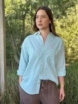 Camisa celeste a rayas verticales blancas, de corte holgado, manga larga y cuello camisero.