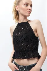 Top negro sin mangas con cuello halter, bordado con calados y volantes en la cintura.