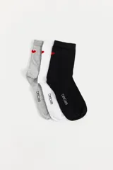 Pack de tres pares de medias Carolcuore, incluye un par gris, un par blanco y un par negro. Cada par cuenta con un pequeño corazón rojo bordado en el lateral superior y la marca escrita en la planta del pie.
