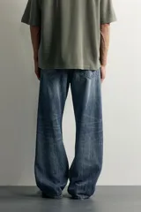 Jeans de denim de algodón en color azul con efecto desgastado, tiro medio y corte recto de ajuste holgado (loose fit). Cuenta con diseño clásico de cinco bolsillos y cierre frontal con cremallera y botón.