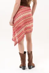 Pollera midi de corte asimétrico con tejido de crochet y patrón en zigzag multicolor en tonos rojo, rosado y beige.