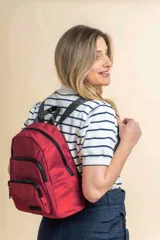 Mochila urbana de diseño funcional en color beige, confeccionada en tela impermeable. Cuenta con un compartimento principal amplio, un bolsillo secundario y un bolsillo frontal, todos con cierre. Incluye asa superior y correas ajustables para los hombros, con detalle de etiqueta de marca en el frente.