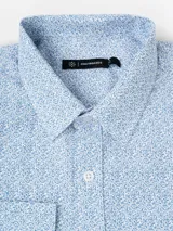 Camisa de manga larga con estampado de puntos finos en color azul sobre fondo blanco, cuello clásico y cierre frontal con botones.