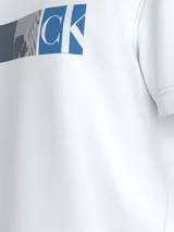 Remera blanca de algodón con cuello redondo y mangas cortas. Presenta un estampado gráfico frontal compuesto por bloques de color gris, negro y verde lima.