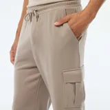 Pantalón de jogging color beige con bolsillos laterales y tobillos ajustados.
