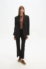 Blazer negro de poliéster, de corte holgado, con cuello solapa y cierre de un botón. Incluye dos bolsillos frontales con solapa y un bolsillo superior simulado.