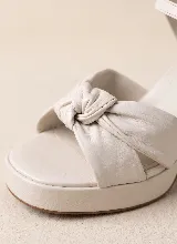 Sandalia de taco alto ancho con plataforma delantera y diseño elegante y sofisticado. Presenta una capellada con tiras anchas y detalle de nudo central. Incorpora pulsera ajustable con hebilla en el tobillo.
