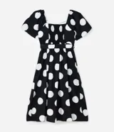 Vestido midi de algodón con estampado de lunares blancos sobre fondo negro. Presenta escote en V, mangas cortas abullonadas, cintura ajustada con cinturón de hebilla y falda con tajo lateral.
