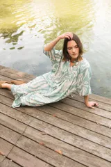Vestido midi de corte camisero con estampado floral en tonos verde agua y crema. Presenta cuello a la base, cierre frontal con botones y mangas al codo con terminación elástica.