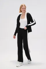 Pantalón ancho de punto color negro con una franja vertical blanca en el lateral.