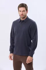 Remera polo de manga larga confeccionada en tejido jersey, con cuello clásico y cierre frontal de tres botones. Presenta un diseño liso con un pequeño logo bordado en el pecho y una etiqueta decorativa en el ruedo.