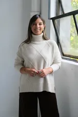 Polerón de cuello alto con diseño de rombos tejidos en relieve, mangas largas con puños acanalados y ruedo asimétrico con aberturas laterales.