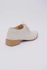 Zapato acordonado de cuero color beige con taco de madera de 3 cm.