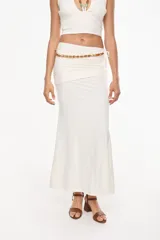 Falda larga blanca de tiro medio-bajo, con fruncido superior, detalle de cuentas marrones en la cintura y caída fluida de estilo boho chic.
