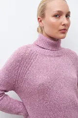 Sweater gris melange de tejido buclé con cuello alto y mangas largas.