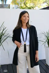 Saco abierto de punto color negro, con mangas largas y bolsillos frontales. Diseño de corte recto y largo medio.