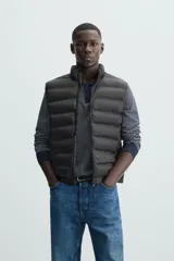 Chaleco acolchado verde oscuro, con cuello alto, cierre frontal con cremallera y bolsillos laterales. Confeccionado en tejido técnico repelente al agua.