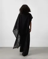 Capa de punto cardado en color negro con diseño asimétrico y bordado calado. Presenta escote redondeado y aberturas laterales. Confeccionada en una mezcla de mohair y lyocell que aporta suavidad y ligereza.