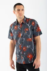 Camisa de manga corta con estampado de palmeras en tonos naranja y blanco sobre fondo gris.
