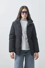 Campera puffer negra con diseño acolchado, capucha integrada y cierre frontal con botones a presión. Presenta puños elásticos y costuras decorativas en el frente.