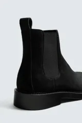 Bota estilo Chelsea de hombre, fabricada en piel con acabado de serraje. Presenta elásticos laterales, horma redonda y suela con ligero tacón.