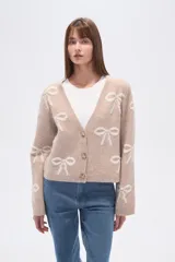 Cárdigan color beige con estampado de moños blancos, escote en V y cierre frontal con botones.