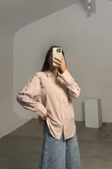 Camisa de lino color rosa pálido, con cuello clásico, cierre frontal de botones y mangas largas con detalles de bordado floral en los hombros y brazos.