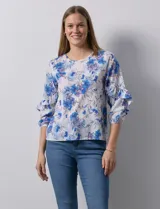 Blusa de gasa estampada con flores azules y violetas sobre fondo blanco, de manga 3/4 con volados.