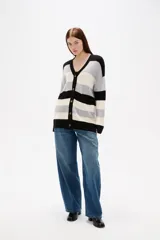 Saco de punto con diseño de rayas horizontales en negro, gris y blanco. Presenta cuello en V, cierre frontal con botones y bolsillos laterales.